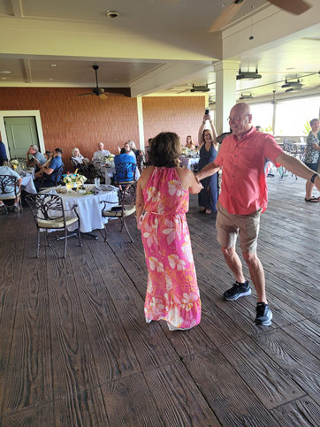 A man and a woman are dancing in a room with tables and chairs.