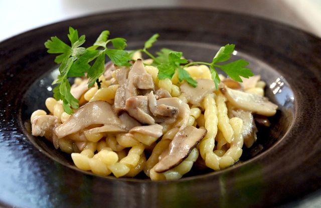 Piatto di pasta con funghi e guarnizione di prezzemolo.
