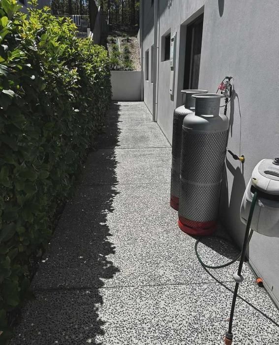 Two Gas Cylinders Are Sitting On A Sidewalk Next To A Building — Clean Cartel Pressure Washing In Reedy Creek, QLD