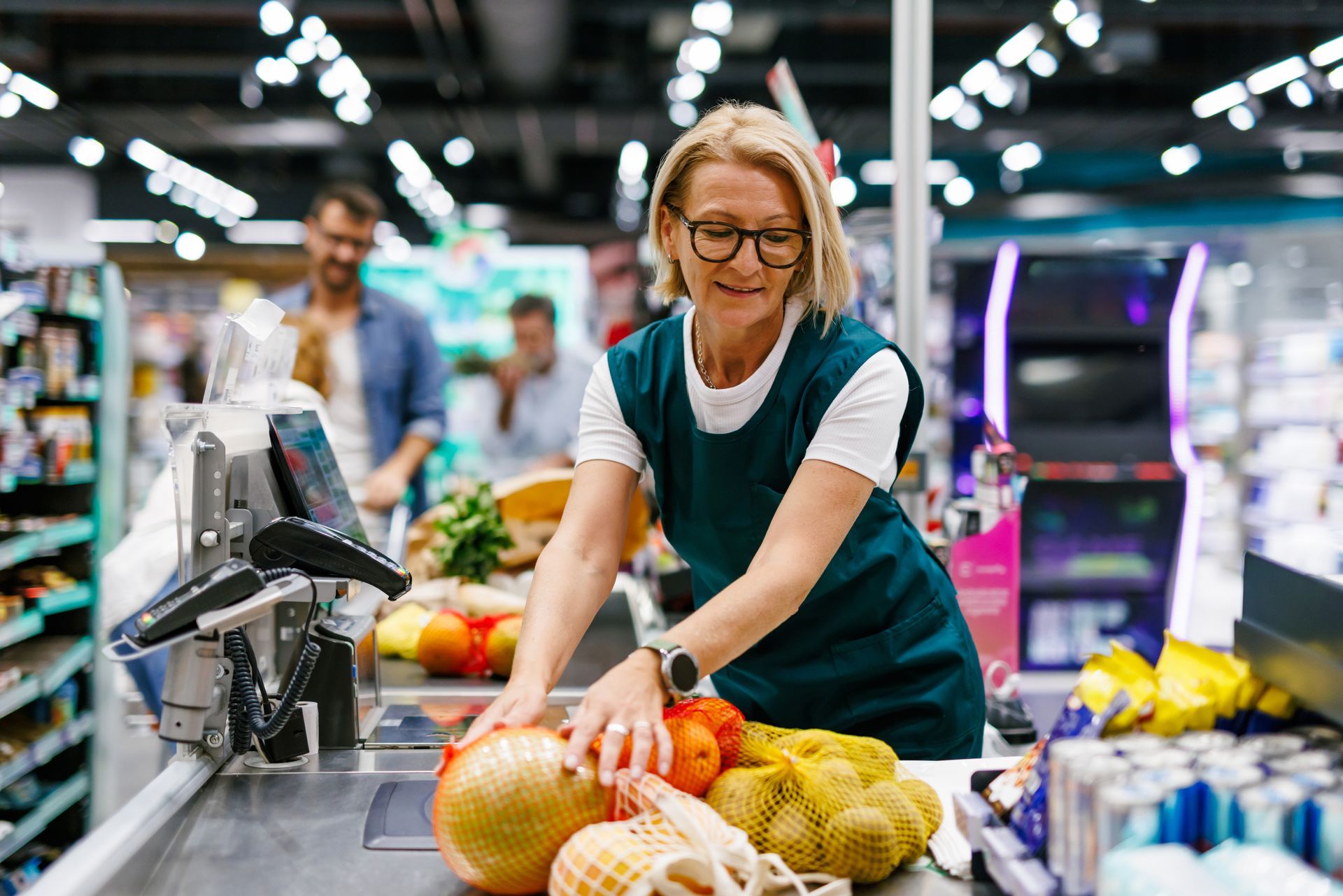 A woman is standing at a cash register in a grocery store.