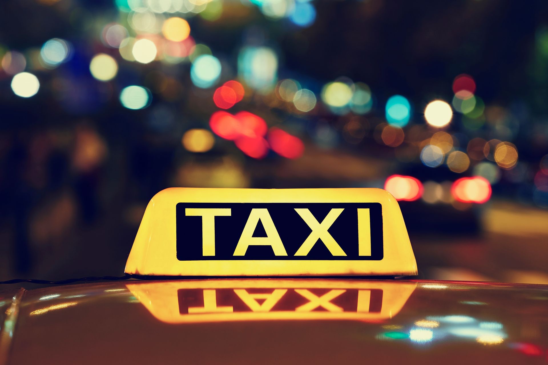 A taxi sign is on the roof of a car