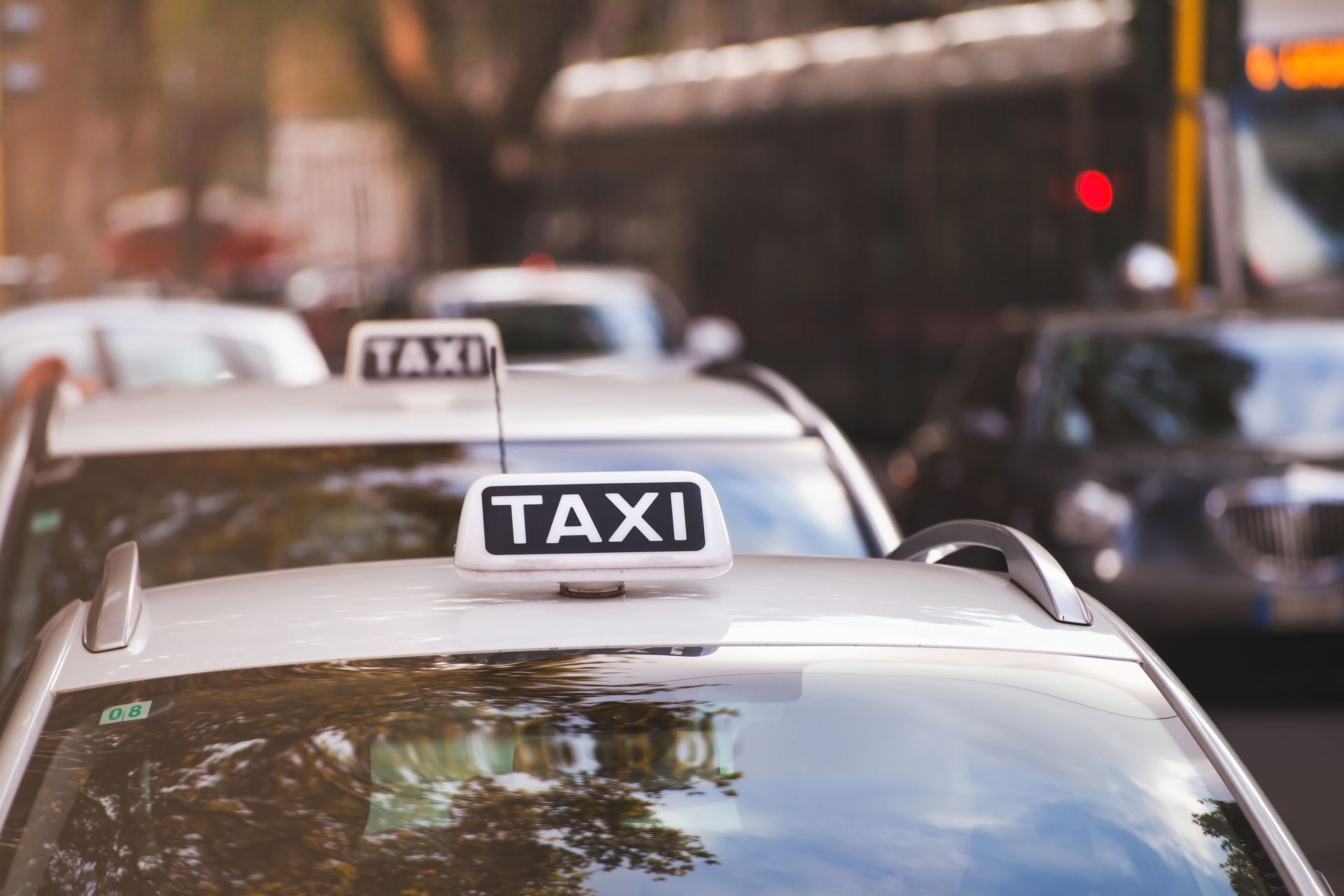 A row of taxi cabs are parked on the side of the road.