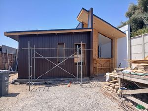 Se está construyendo una pequeña casa con andamios delante de ella.