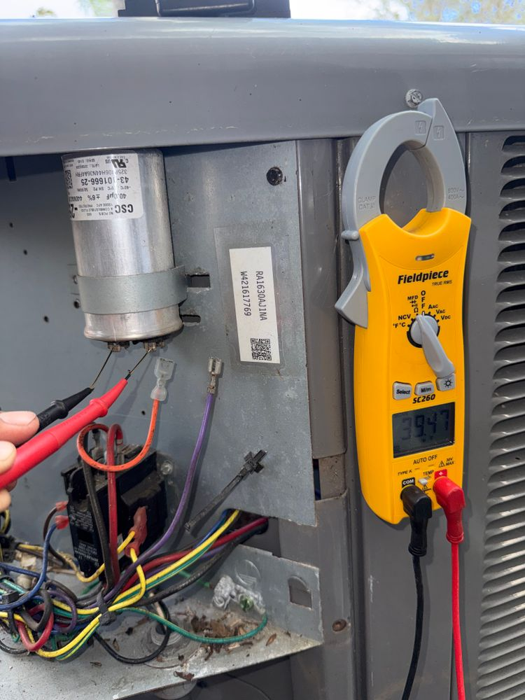 Inside an electrical panel, red probe testing wires beside a yellow multimeter.