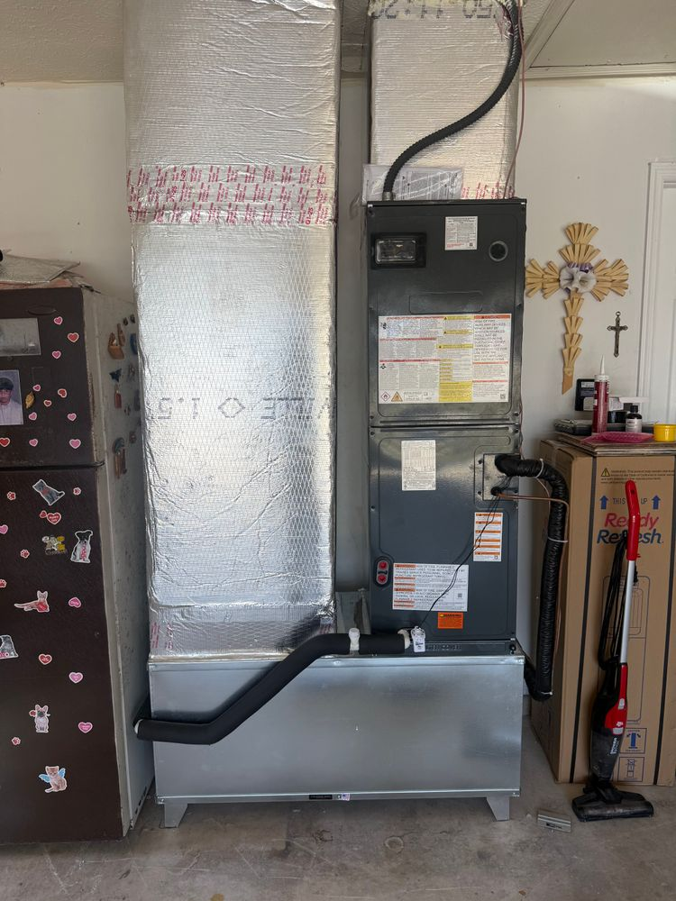 Furnace and HVAC ductwork in a garage utility area with a vacuum hose and cleaning tools nearby