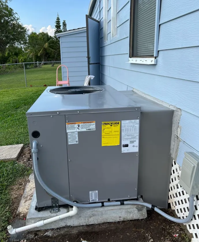 Outdoor HVAC unit beside a blue house with white trim and a window.