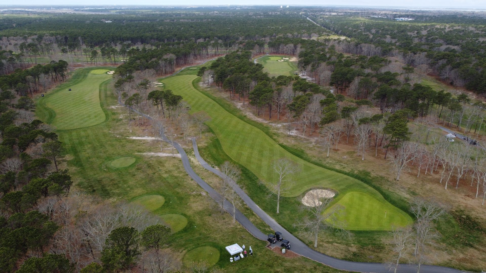 An aerial view of a golf course surrounded by trees.