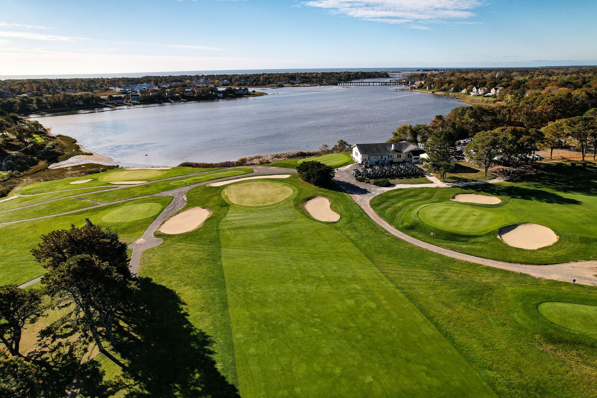 An aerial view of a golf course with a lake in the background.