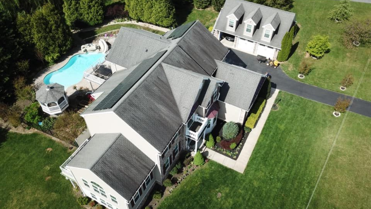 Aerial view of a large house with a pool and gazebo; driveway leads to a three-car garage.