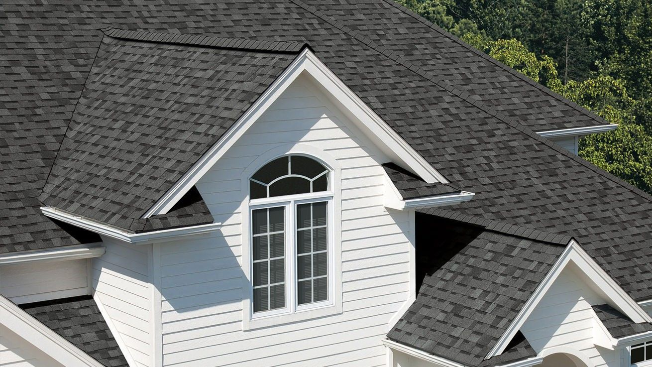 White house with dark gray shingle roof and a gable window.