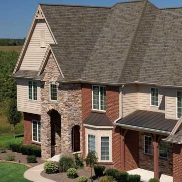 A large brick house with a brown roof and white siding.