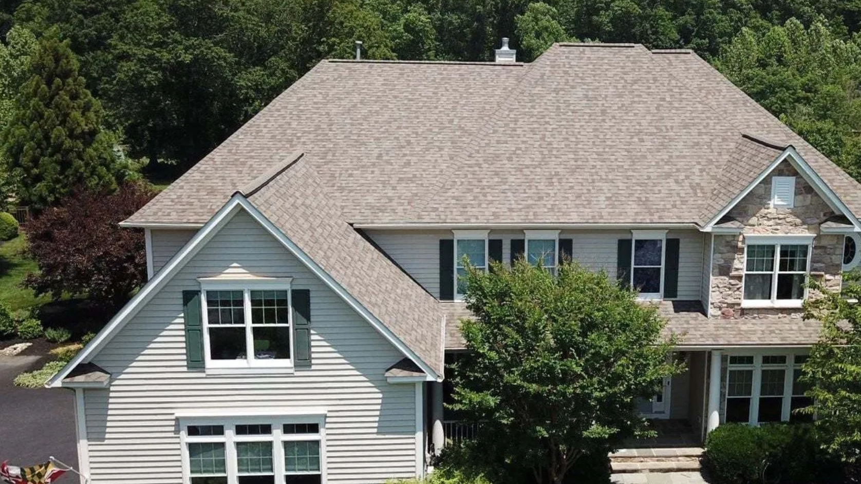 Beige two-story house with gray roof. White siding installed perfectly