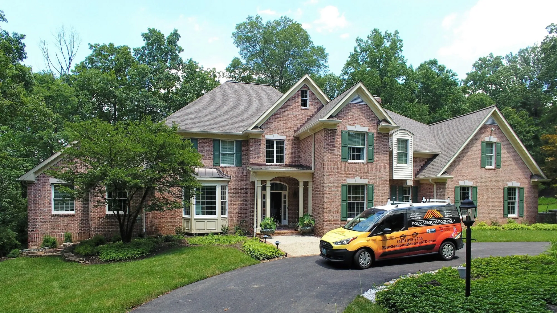 Brick house with a service van in the driveway. Trees frame the house on a sunny day.