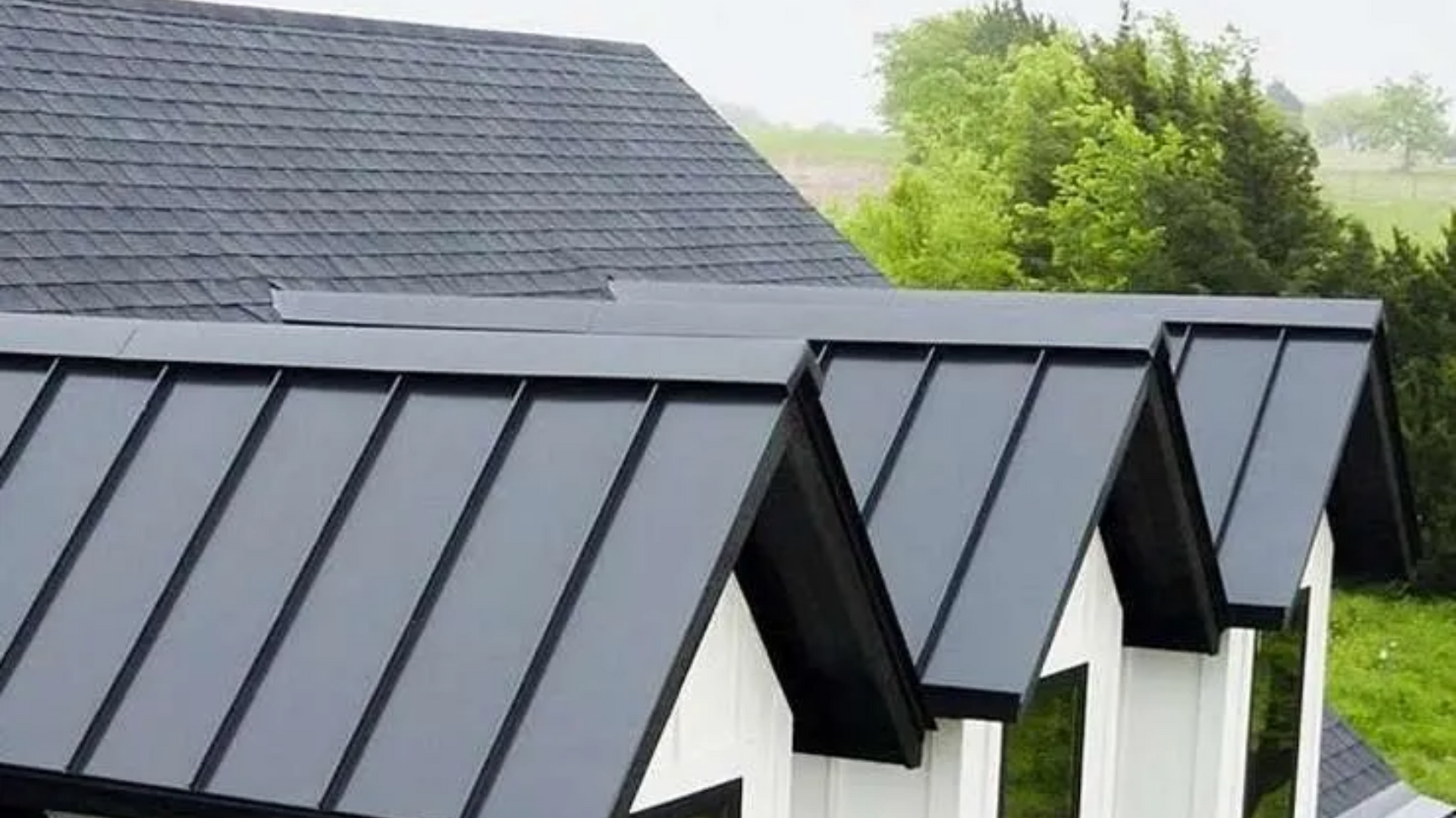 Black metal roof sections on a white building. Flawlessly installed by Four Seasons