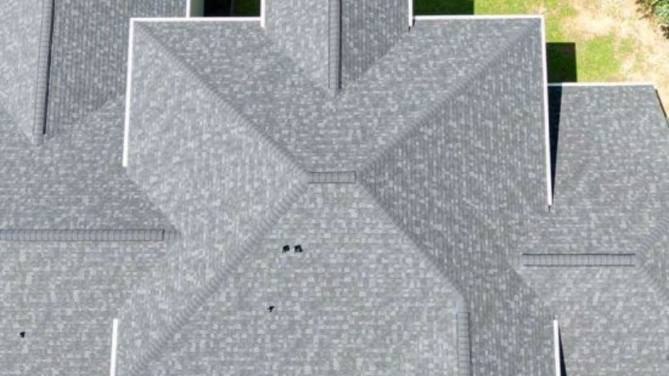 Overhead view of a gray asphalt shingle roof with multiple gables and white trim.