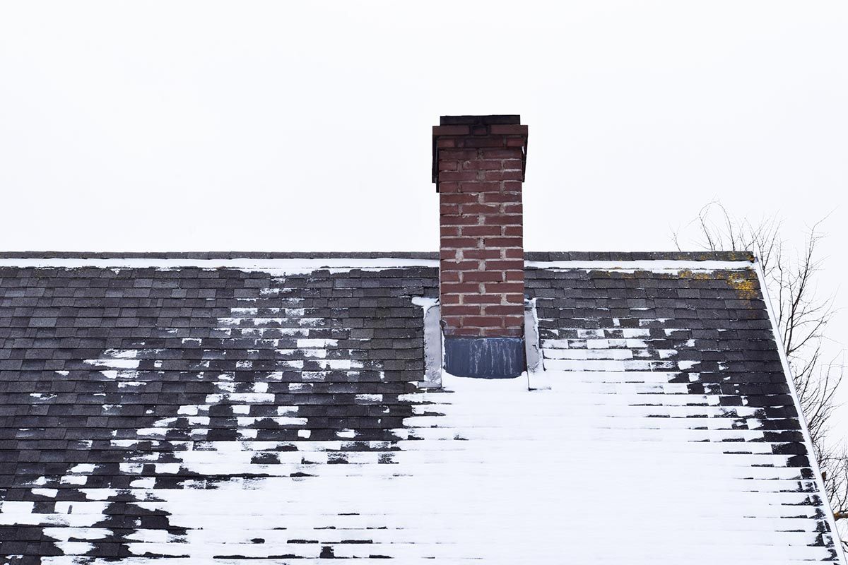 Residential roof with snow melting at different rates due to heat escaping unevenly.