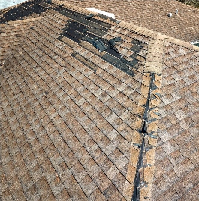 Damaged brown tiled roof with a large repaired section and visible broken tiles