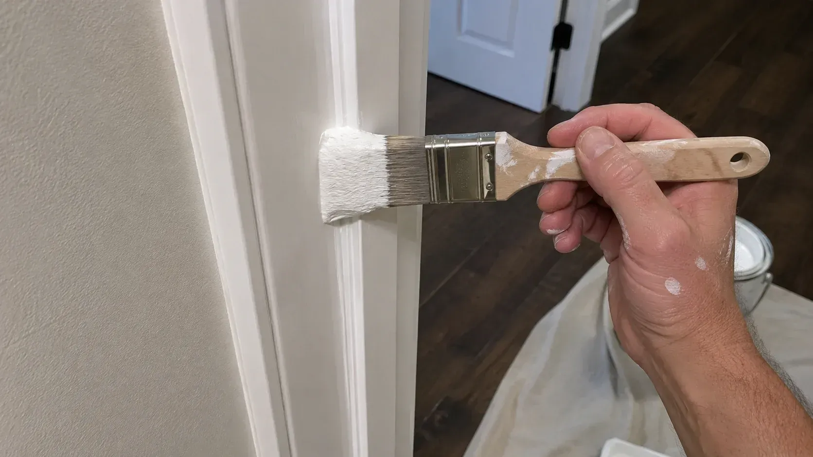 Painter applying trim paint with a brush: is enamel paint better than latex for home interiors.