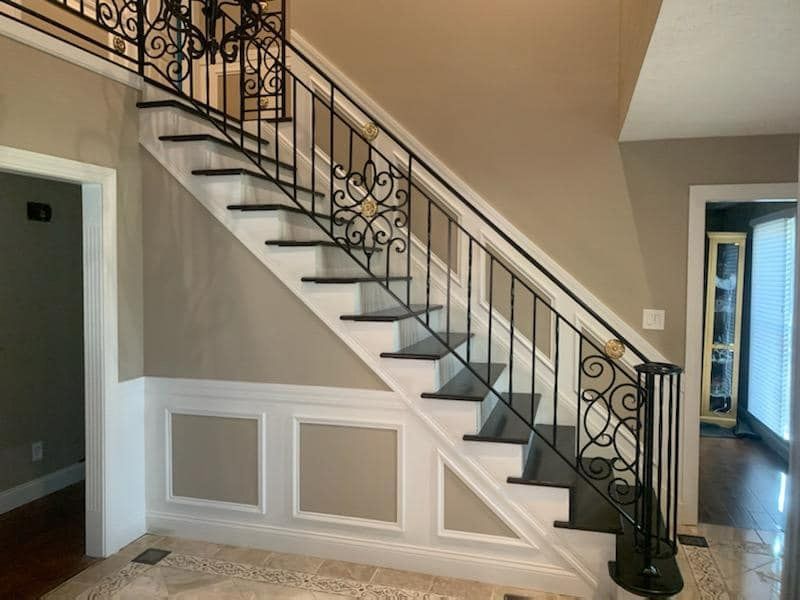 A staircase in a house with a wrought iron railing