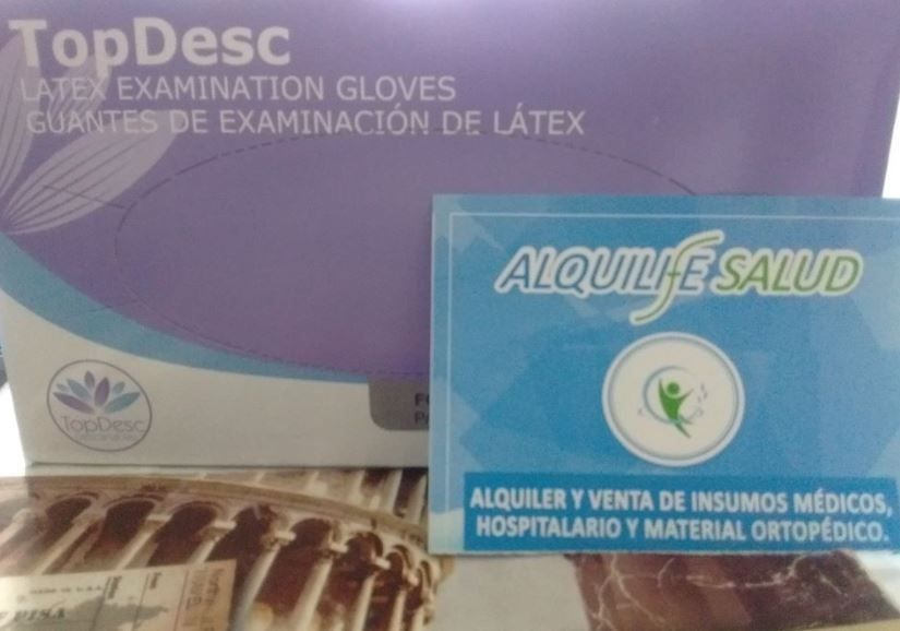 Cajas de guantes médicos con un letrero azul de Alquife Salud en primer plano.