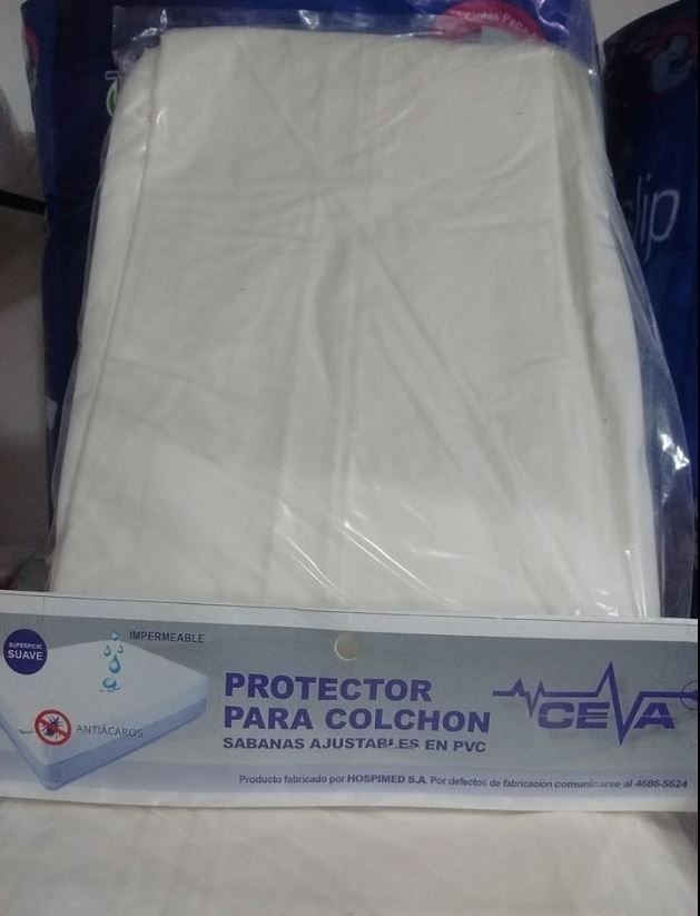 Protector de colchón blanco empaquetado en plástico transparente con etiqueta azul que dice “Protector para colchón”