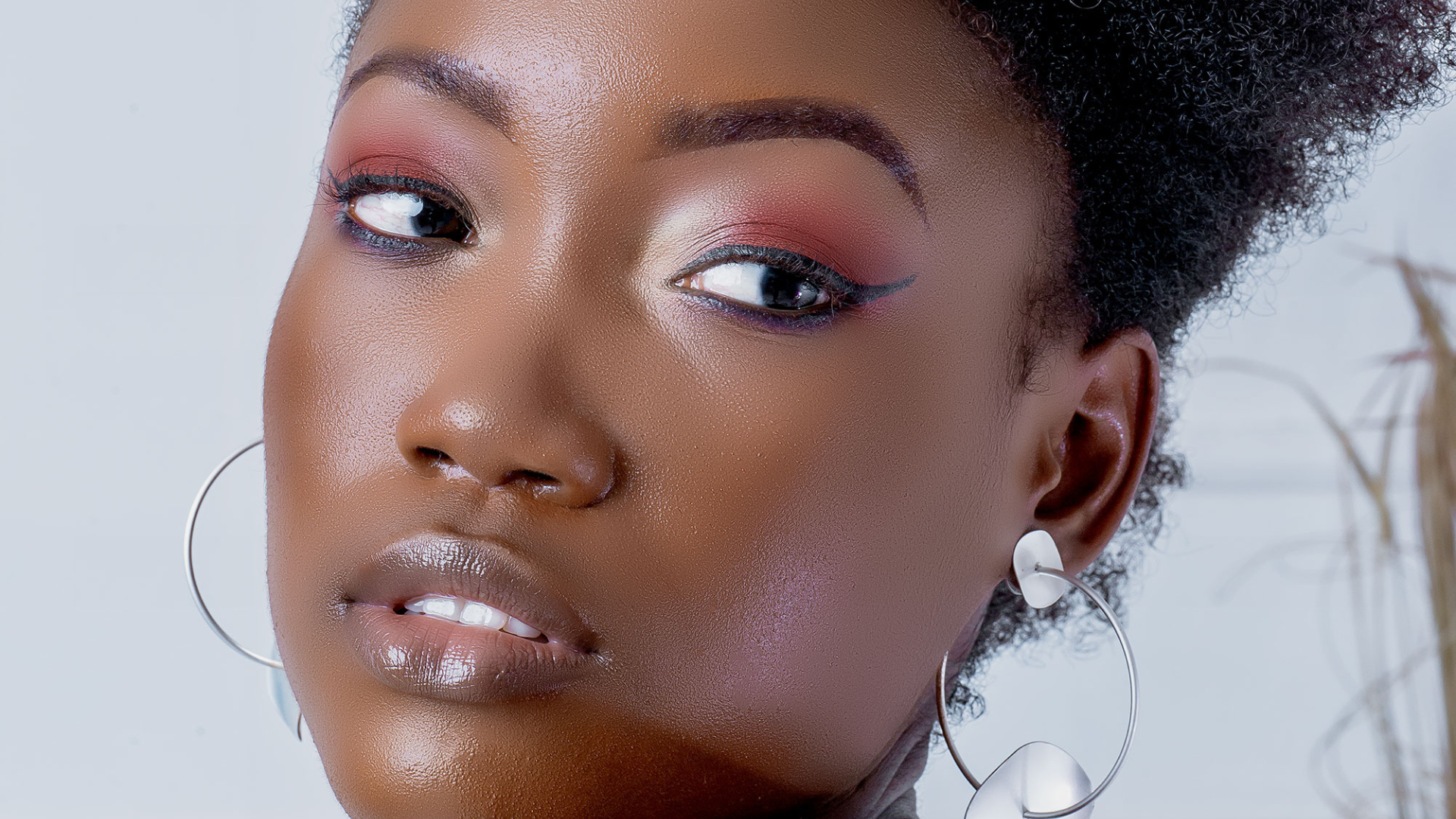 A close up of a woman 's face with makeup and hoop earrings.