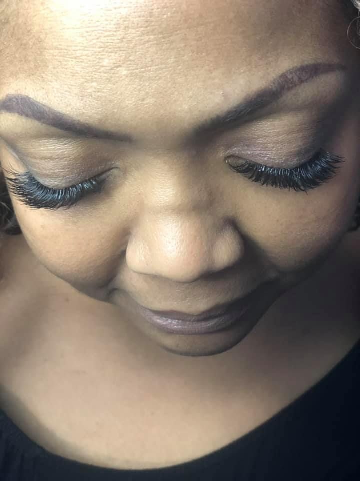 Woman with closed eyes, full eyelashes, and filled-in eyebrows. She's wearing a black top.