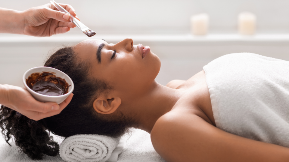 Person receiving a facial treatment with hands cupping the face, eyes closed.