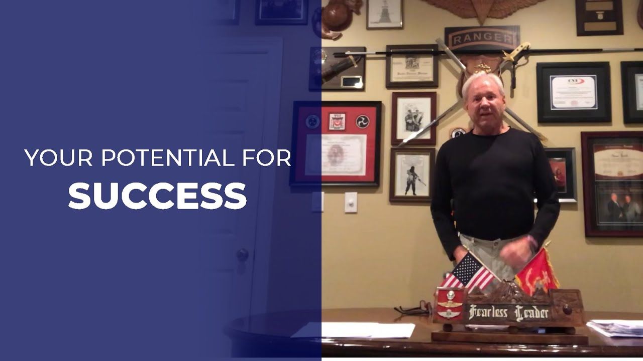 Man standing at a desk with flags; text reads 