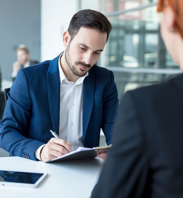A Man In A Blue Suit Is Writing On A Piece Of Paper — Charlestown Law Firm In Lake Macquarie, NSW