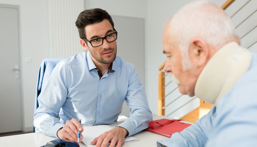 A Man Is Talking To An Older Man With A Neck Brace — Charlestown Law Firm In Maitland, NSW