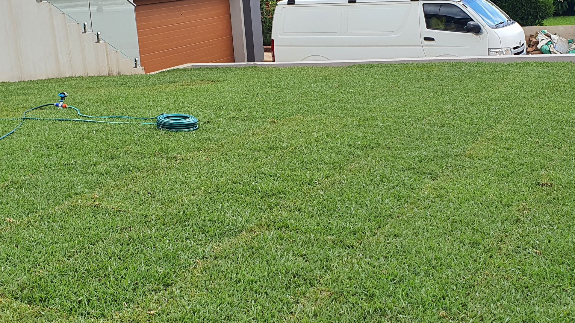 A white van is parked in front of a lush green lawn.