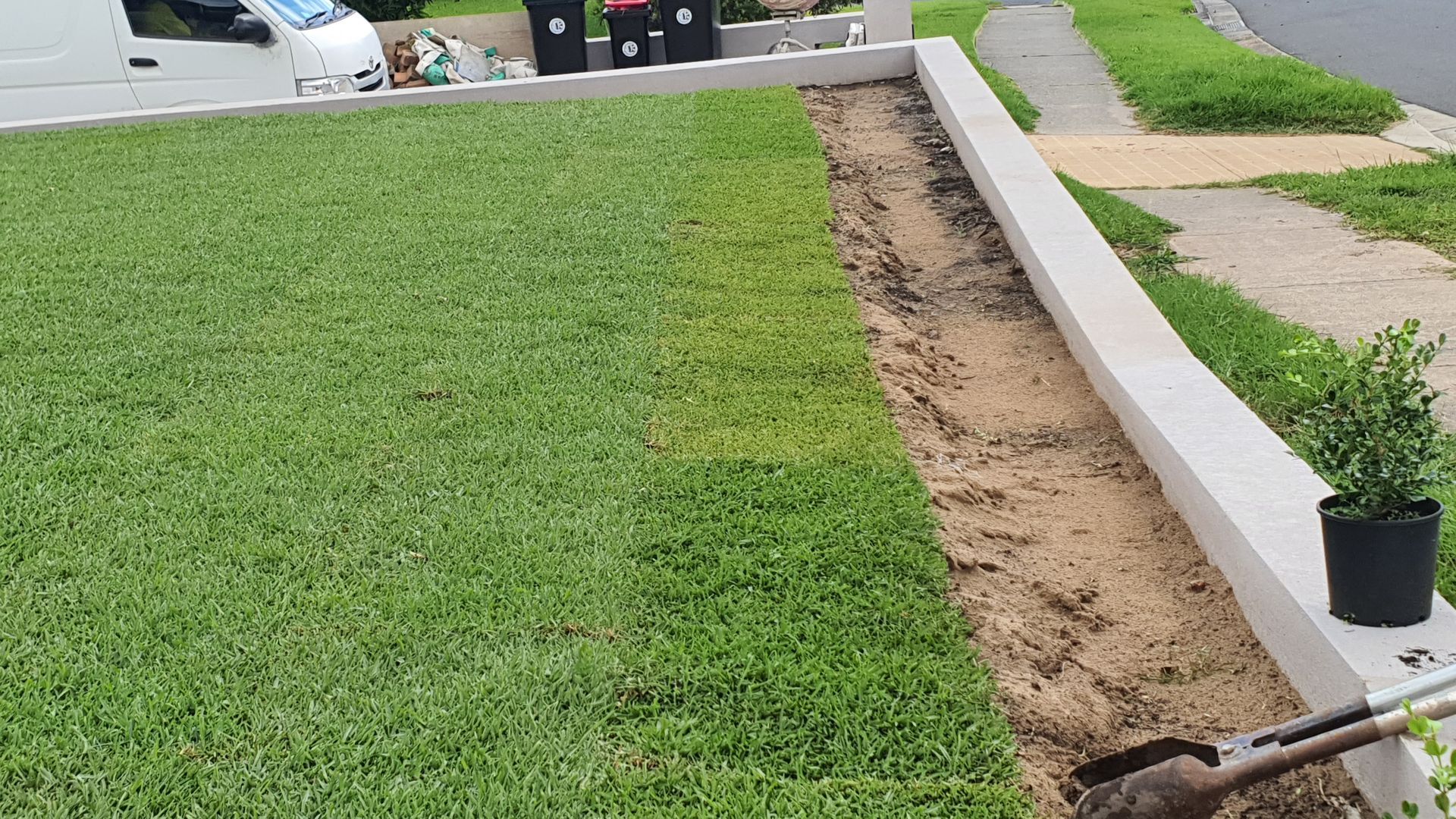A shovel is sitting on the side of a lush green lawn.