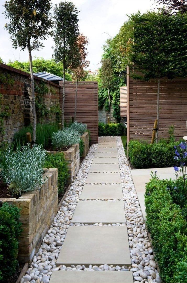A stone walkway leading to a house in a garden.