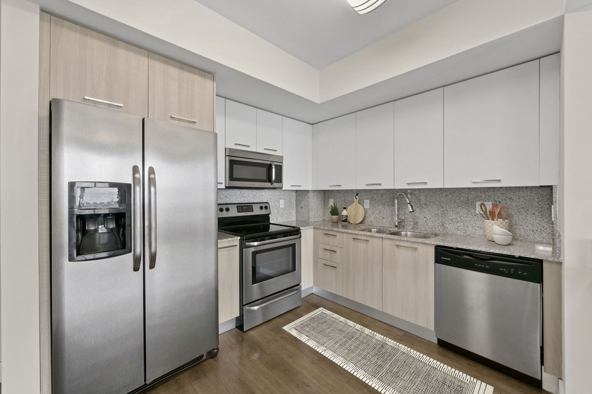 Modern kitchen with stainless steel appliances, white cabinets, and gray countertops.