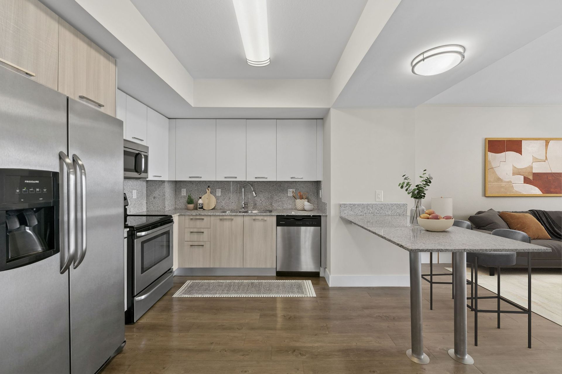 Modern kitchen with stainless steel appliances, white cabinets, and a small dining table.