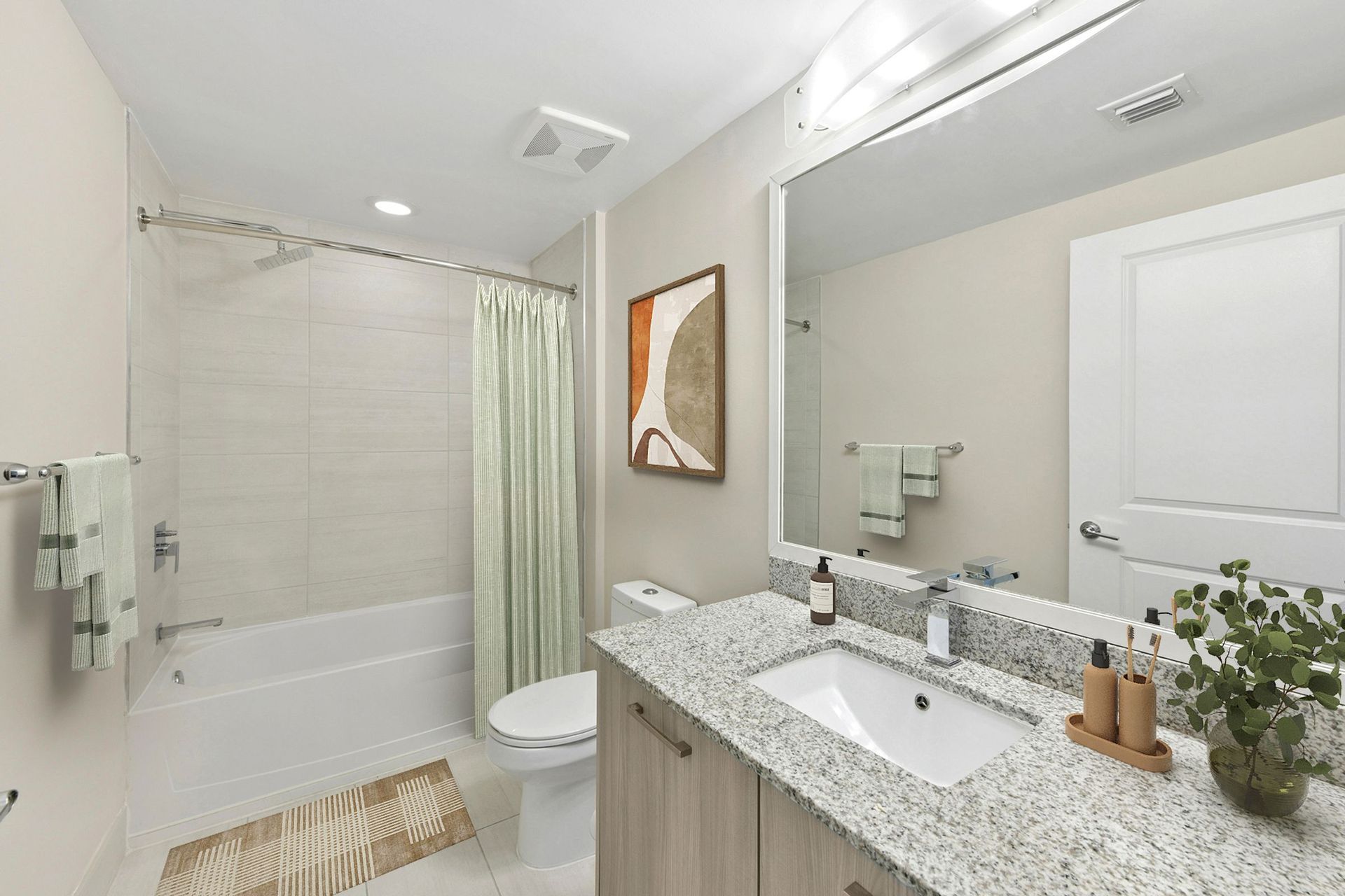 Bright bathroom with tub, shower curtain, large mirror, and granite vanity countertop.