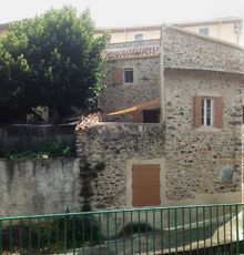 the back of a brick house with a green gate in the foreground