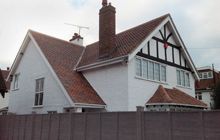 a white house with a slanted roof and a brown fence in the foreground