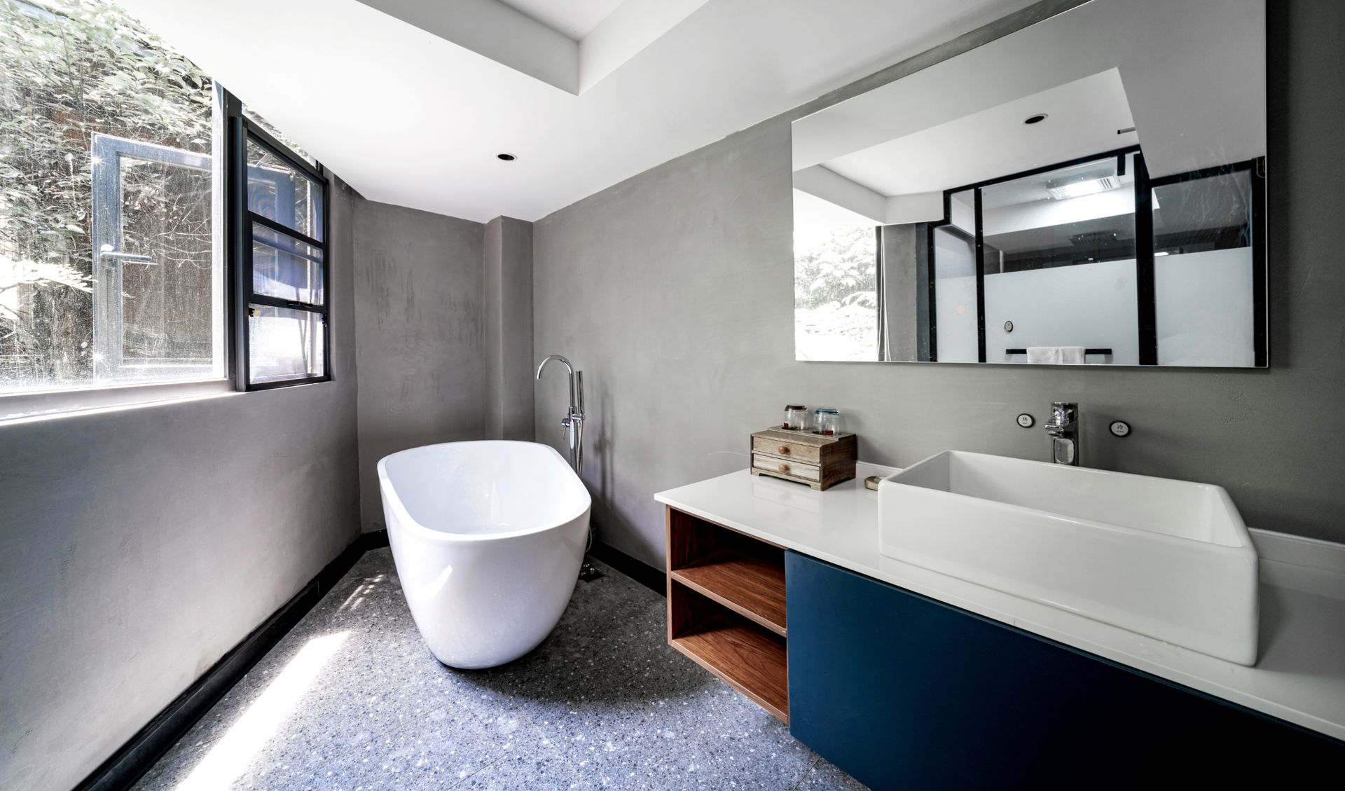 Modern bathroom with freestanding tub, large mirror, and vanity in gray and white tones