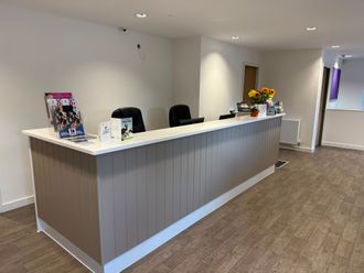 Empty reception desk in a modern hallway with a white countertop and brown paneling.