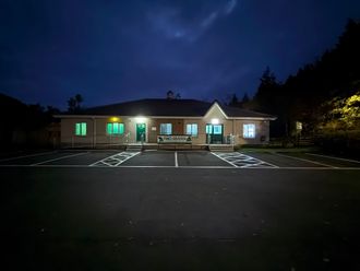 Empty parking lot in front of a lit building at night under a dark blue sky