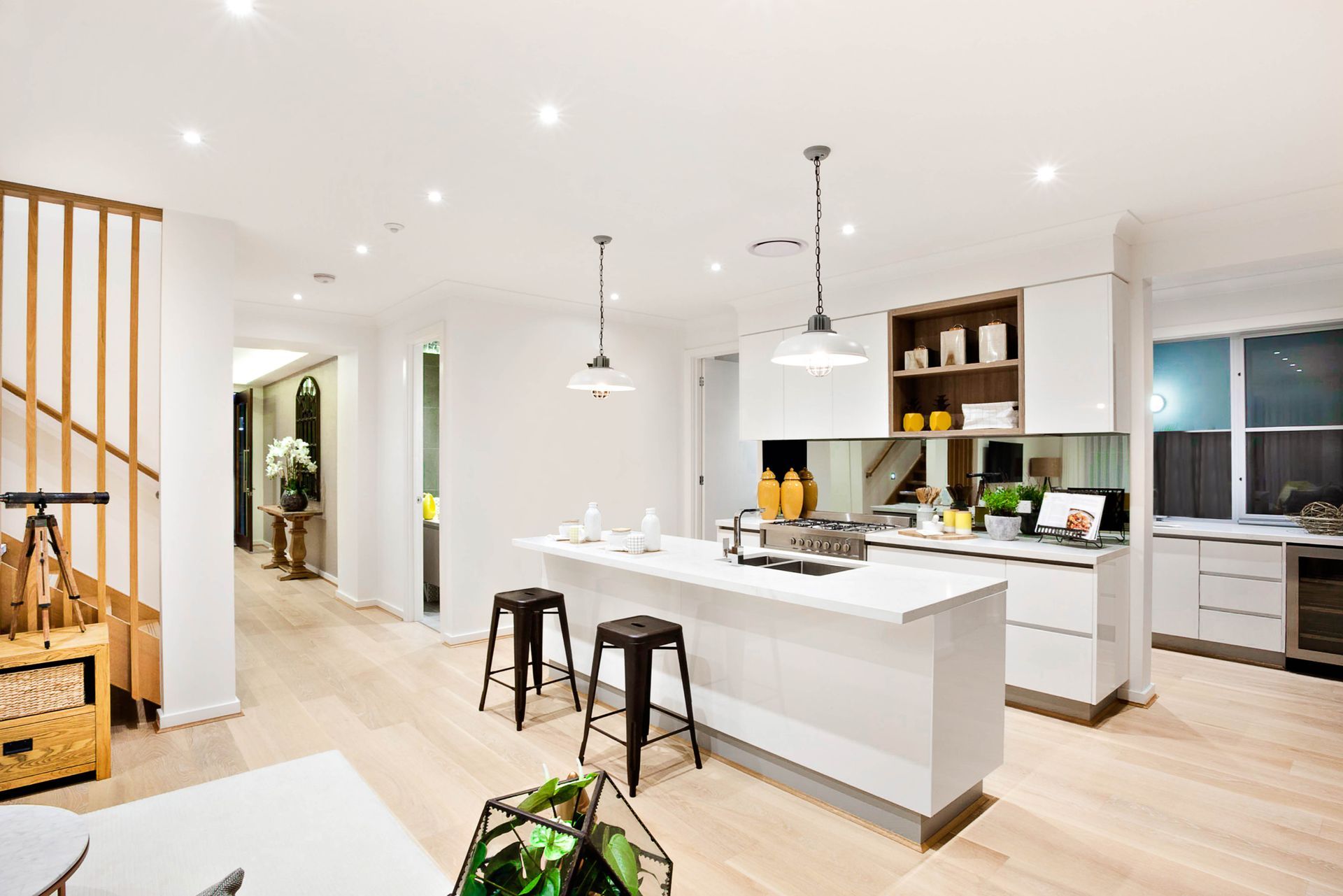 Bright modern kitchen with white island, bar stools, pendant lights, and open shelving in a spacious home