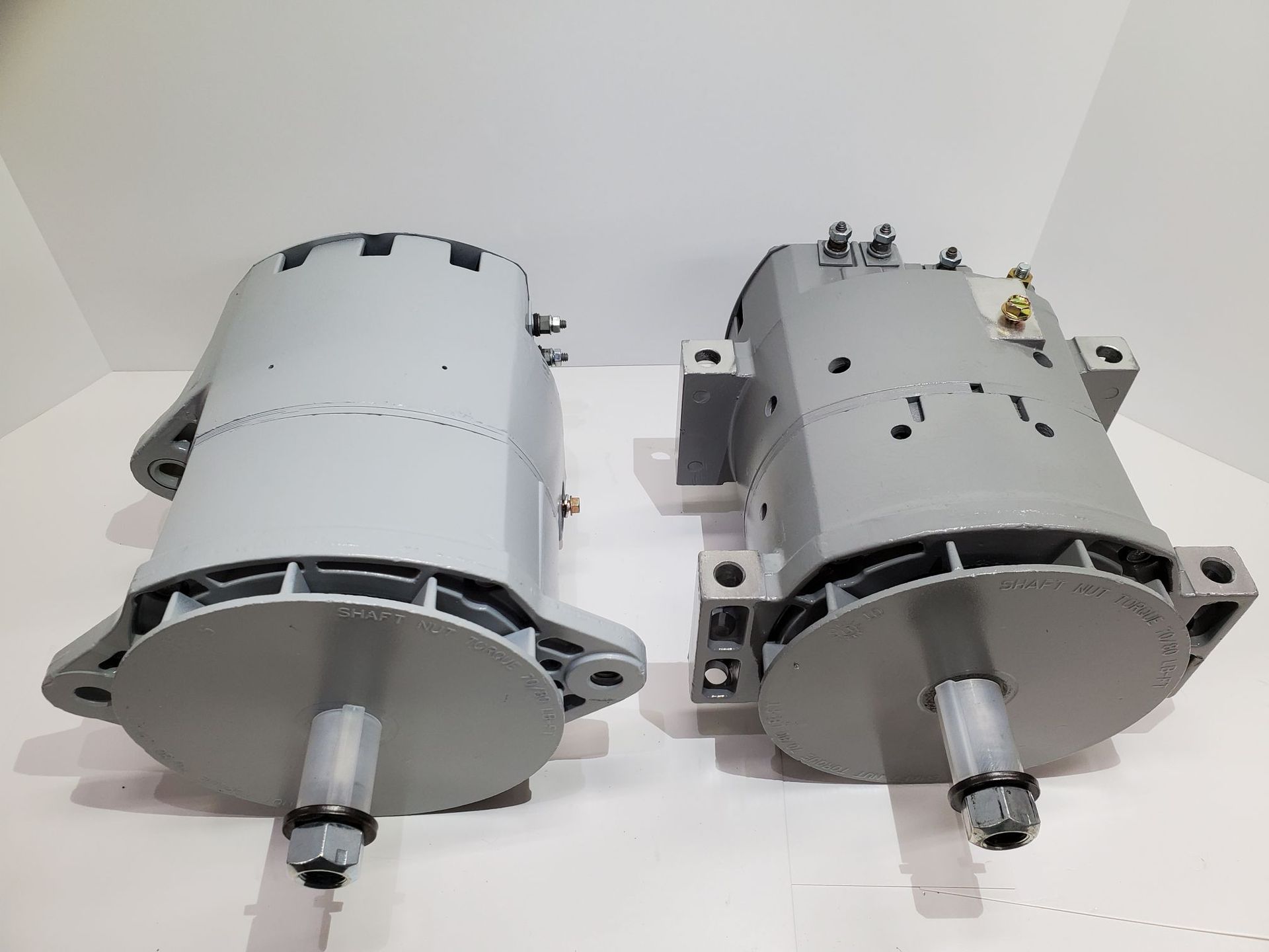 Two gray electric motors side by side on a white surface