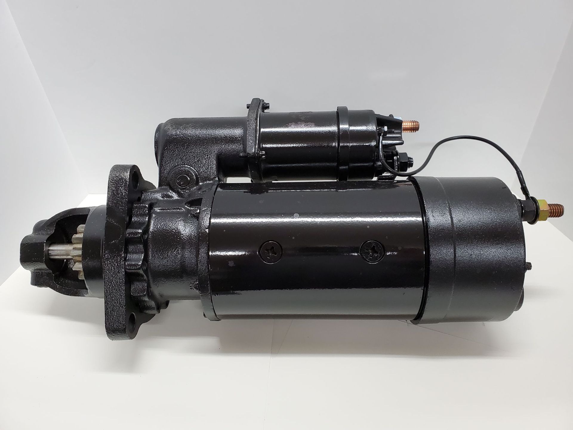 Black starter motor assembly with attached solenoid on a white background