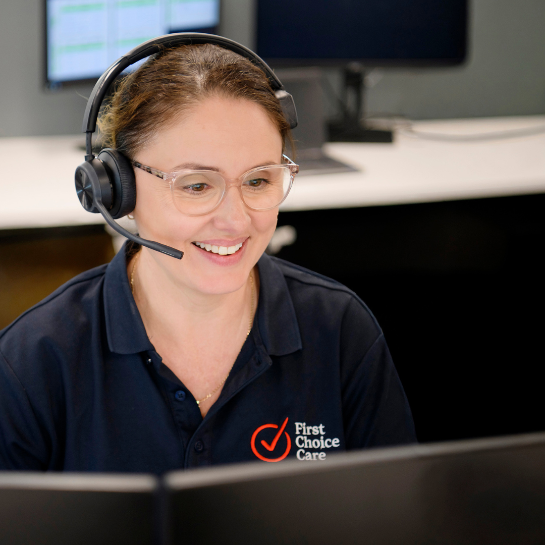 Smiling customer service agent in a headset at a computer in an office