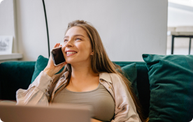 Woman on a green couch looks at her phone, resting her chin on her hand.