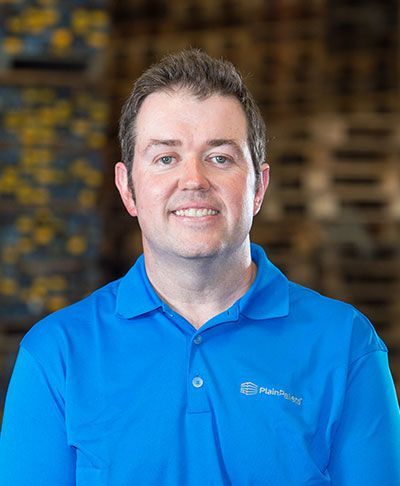 A man wearing a blue polo shirt is smiling for the camera. A man wearing a blue polo shirt is smiling for the camera.