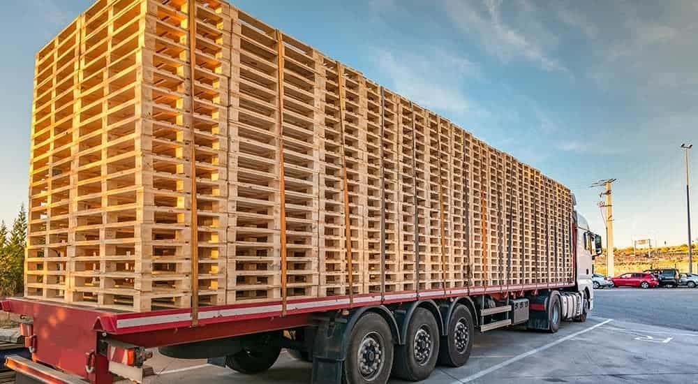 A truck filled with lots of wooden pallets is parked in a parking lot. A truck filled with lots of wooden pallets is parked in a parking lot.