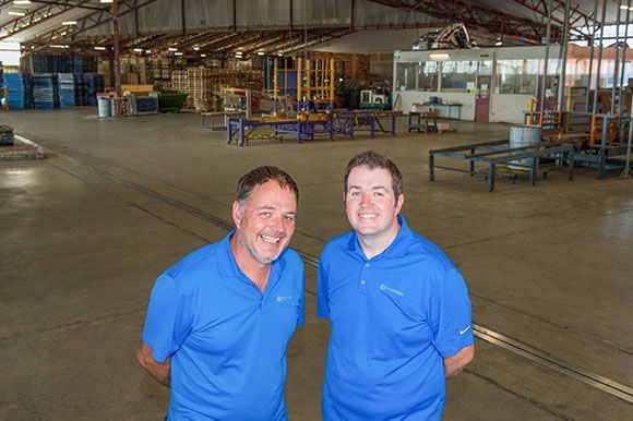 Two men in blue shirts are standing in a large warehouse. Two men in blue shirts are standing in a large warehouse.